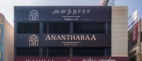 Un hotel con un letrero que dice 'Anantharaa Hotel' y una joyería debajo llamada 'Kalyan Jewellers'.