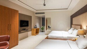 Una camera d'albergo moderna con due letti, una TV, un armadio in legno e una scrivania con una pianta.