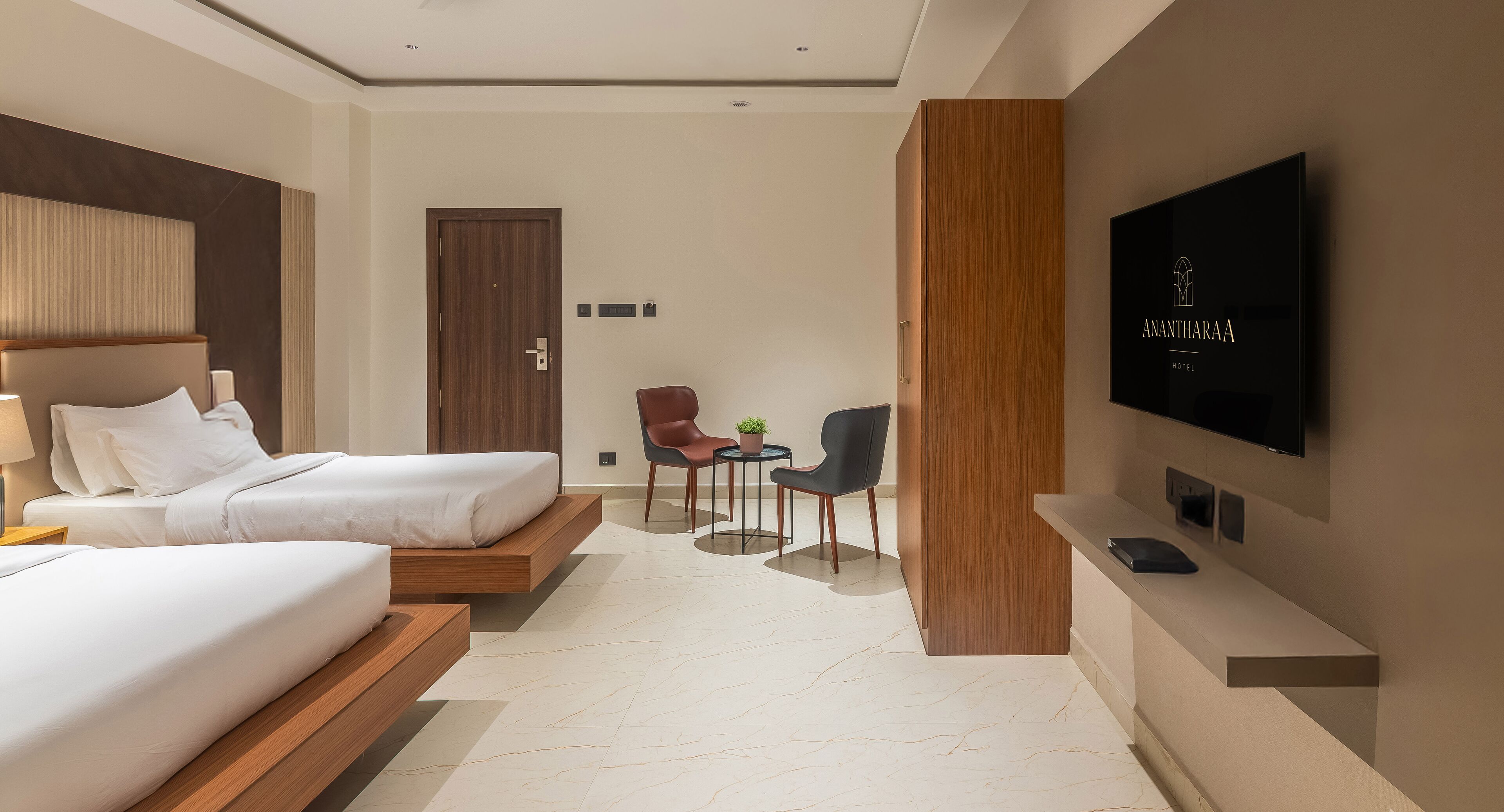 Habitación de hotel con dos camas, televisión, escritorio y silla.