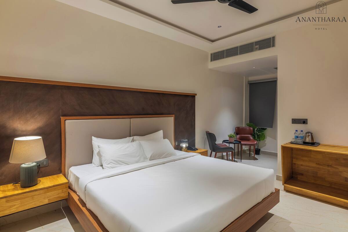 A hotel room with a large bed, a desk, a chair, a lamp, and a ceiling fan.