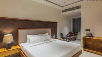 A hotel room with a large bed, a desk, a chair, a lamp, and a ceiling fan.