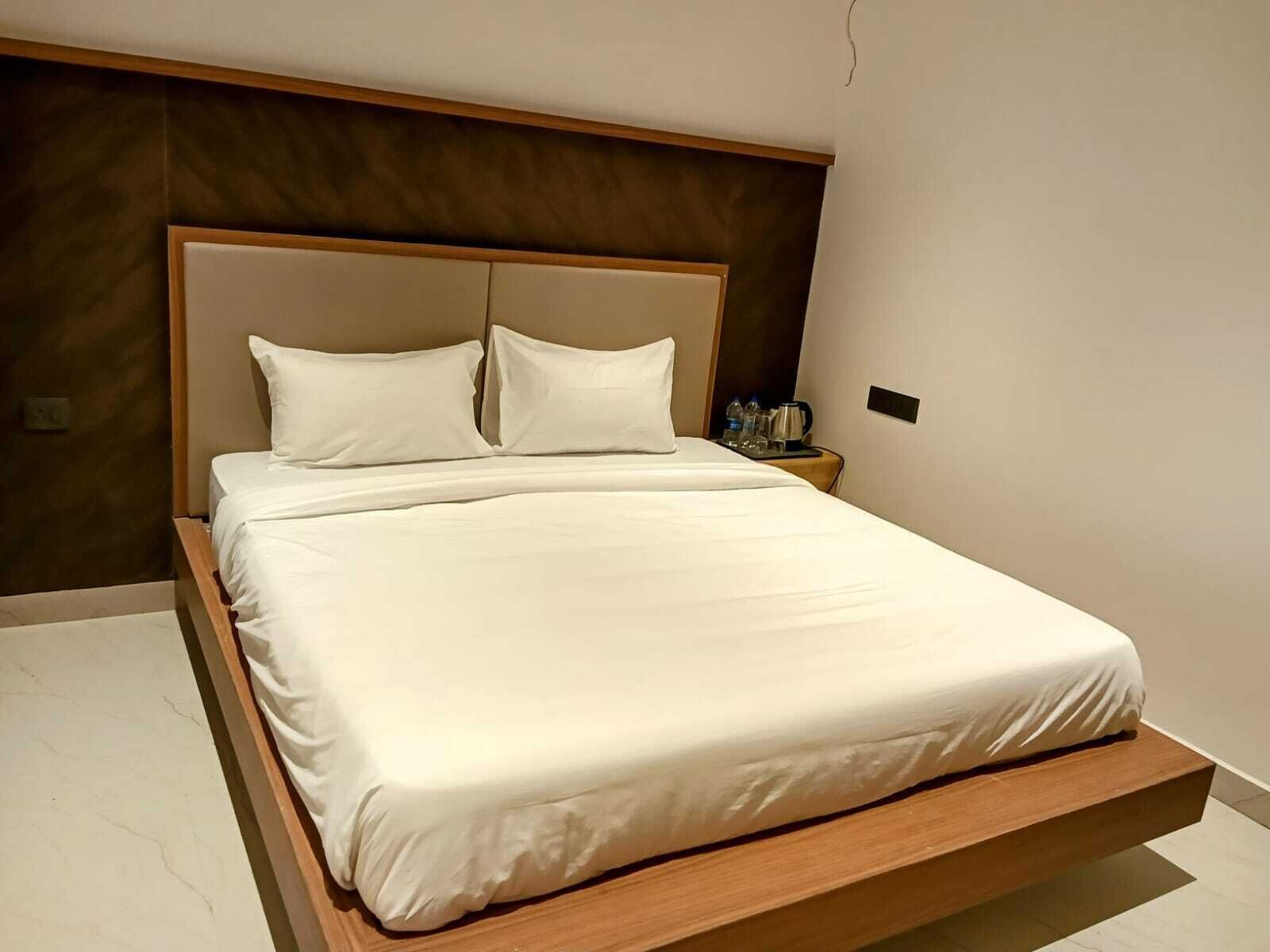 A modern bed with a wooden frame and white bedding in a hotel room.