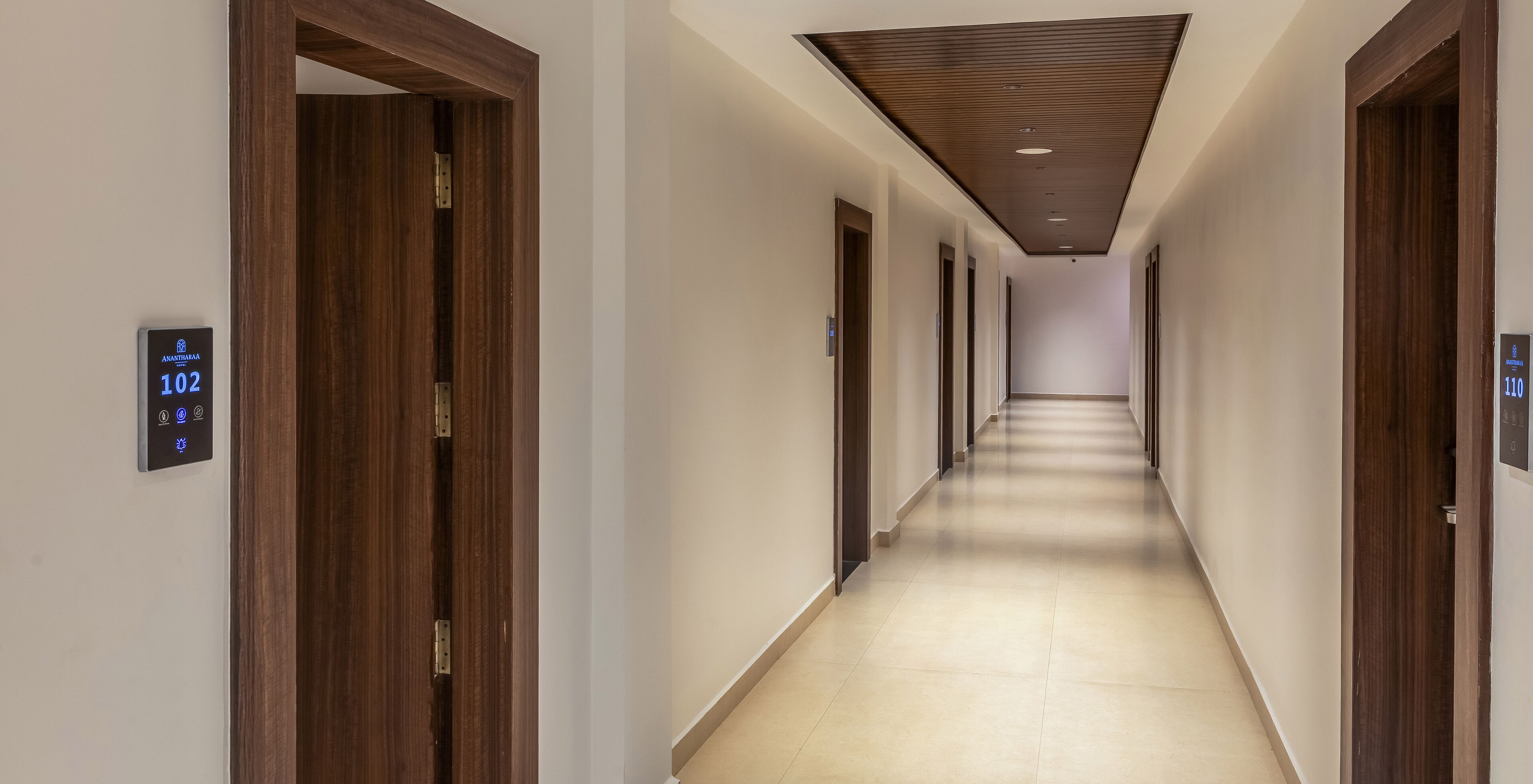 Un largo y estrecho pasillo de hotel con puertas de madera a ambos lados y suelo de color claro.