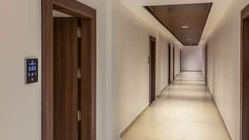 A long, narrow hotel corridor with wooden doors on either side and a light-colored floor.