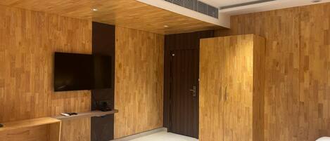 A modern bedroom with wooden paneling, a flat-screen TV, a bed, and a ceiling fan.