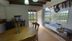 Un comedor con una mesa y sillas de madera, un florero con flores y vistas al exterior a través de amplios ventanales.