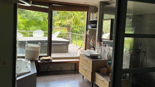 A modern bathroom with a large window, a bathtub, a sink, and a shower area. - Villa Oana (Paron)