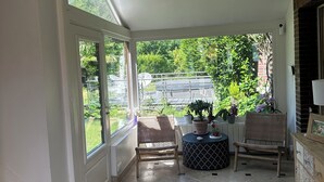 A covered patio with a tiled floor, two wicker chairs, a small round table, and potted plants. - Villa Oana (Paron)