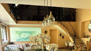 A spacious dining area with a large wooden table, upholstered chairs, and a chandelier. A staircase is visible in the background leading to an upper level. - Villa Oana (Paron)