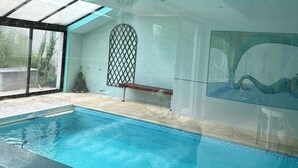 An indoor swimming pool with a clear glass ceiling, a bench, and a decorative wall mural. - Villa Oana (Paron)