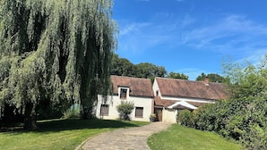 A traditional house with a brick pathway leading to the entrance, surrounded by lush greenery and a large weeping willow tree. - Villa Oana (Paron)
