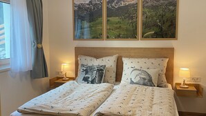 A double bed with a wooden headboard, two bedside tables with lamps, and three framed landscape paintings above the bed. - Beagzeit Ferienwohnung (Lofer)