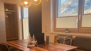A dining area with a wooden table, two chairs, a bench, and pendant lights. - Beagzeit Ferienwohnung (Lofer)