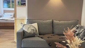 A modern living room with a grey sofa, a round wooden coffee table, and a wall-mounted light fixture. - Beagzeit Ferienwohnung (Lofer)