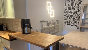 Eine Küche mit Holzarbeitsplatte, einer Kaffeemaschine, einer Mikrowelle und einem Handtuchhalter an der Wand.