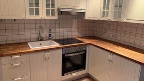 Eine Küche mit weißen Schränken, einer Spüle, einem Herd und einer Mikrowelle.