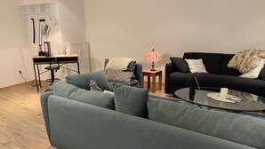 Ein modernes Wohnzimmer mit einem grünen Sofa, einem schwarzen Sofa, einem kleinen Tisch mit einer Lampe und einer Heizung.