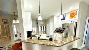 A modern kitchen with granite countertops, stainless steel appliances, and bar seating. - Charming Lakeview Home, Heated Saltwater Pool, WiFi, All New Furniture (Venice)