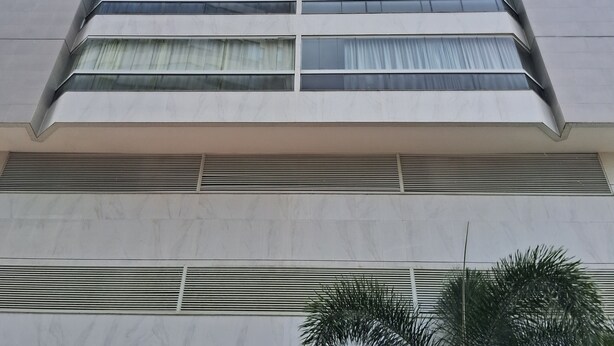 Un edificio alto y moderno con varios pisos, grandes ventanales y techo plano.