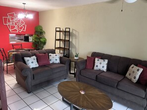 A living room with two sofas, a coffee table, and a red accent wall. - Charming 2-bedroom apartment in wonderful Montego Bay with WiFi, AC (Montego Bay)