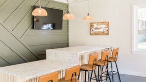 A kitchen with a marble countertop, wooden chairs, and pendant lights. - The Lounge- Heated Private Bar, Hot Tub, Fire Pit, Sleeps 14 (Cincinnati)