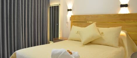 A hotel room with a large bed, two pillows, a neatly folded towel, and a nightstand with a lamp.
