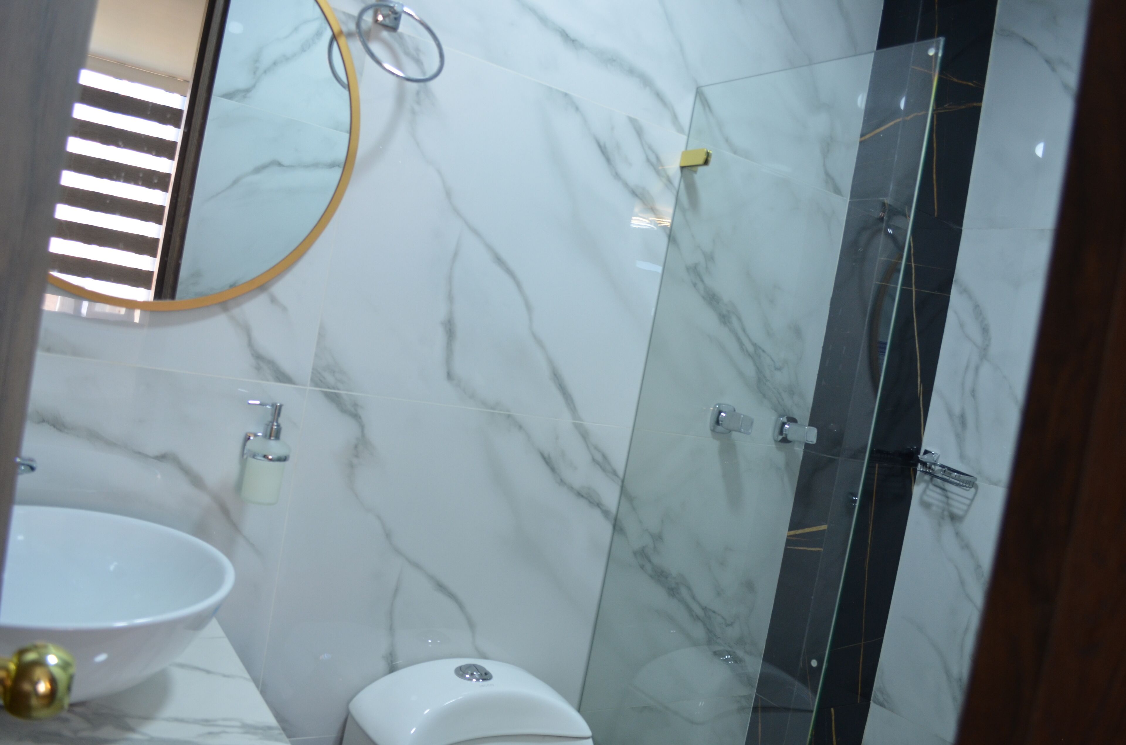 Une salle de bain avec un lavabo en marbre, des toilettes et une douche séparée par une paroi de verre.
