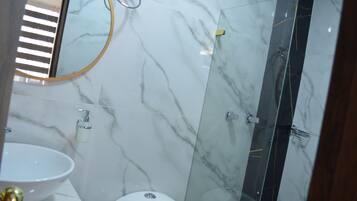 Une salle de bain avec un lavabo en marbre, des toilettes et une douche séparée par une paroi de verre.