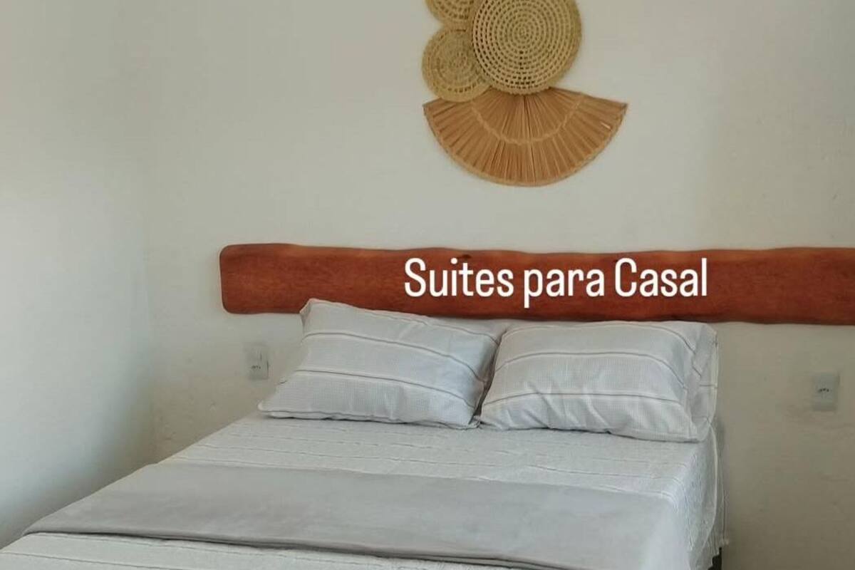 Una camera da letto con un letto, cuscini, una testiera e decorazioni a parete.
