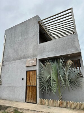 Un edificio moderno con fachada plana, puerta de madera y un letrero que dice 'Villa Maite'.