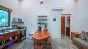 Une cuisine avec un bar en bois, des tabourets, un ventilateur de plafond et un appareil de climatisation.