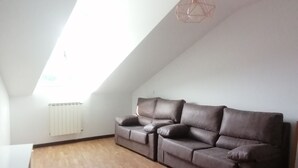 A spacious living room with a high ceiling, a brown leather sofa, a wooden floor, and a skylight. - 3 bedrooms penthouse in the center of Cangas de Onis (Cangas de Onís)