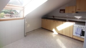 A kitchen with white cabinets, a stove, and a window overlooking a residential area. - 3 bedrooms penthouse in the center of Cangas de Onis (Cangas de Onís)