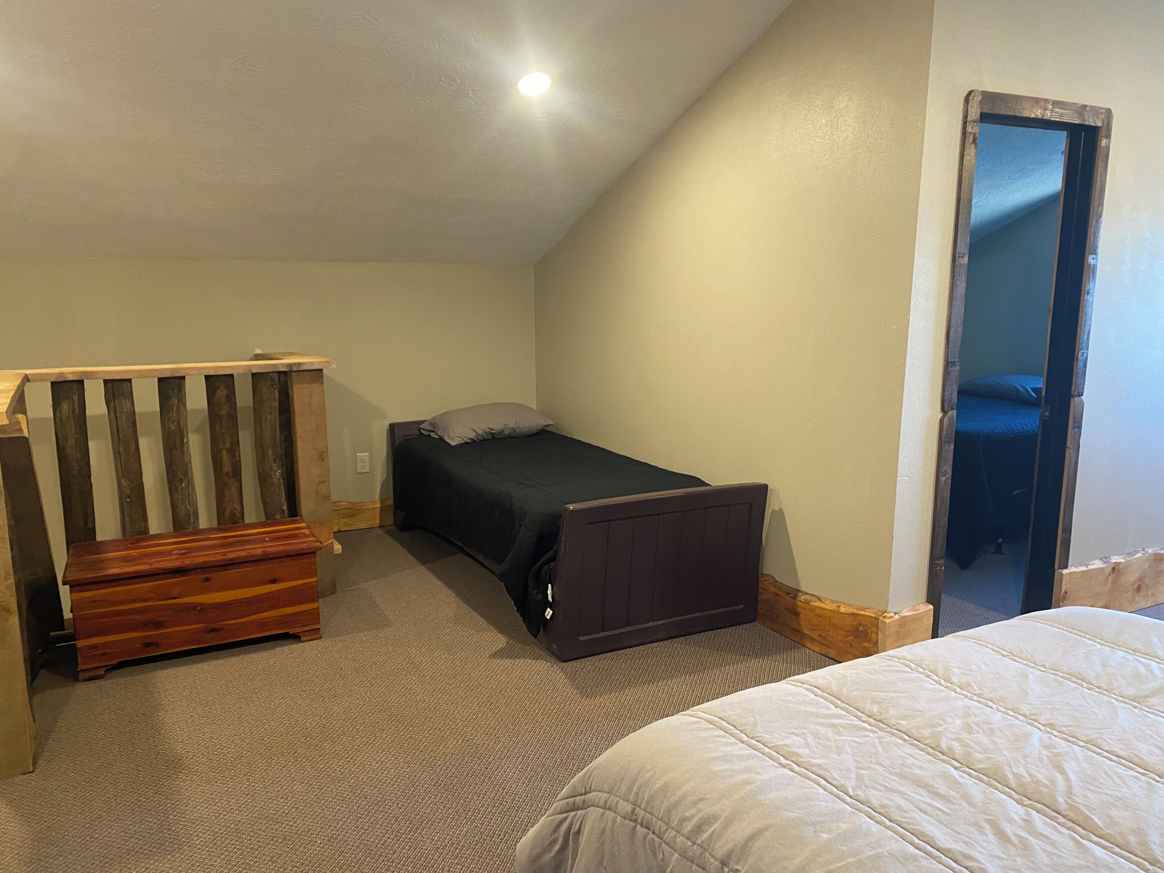 Una habitación pequeña y compacta con una cama individual, un banco de madera y un escritorio pequeño.