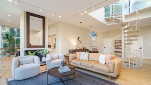 Un salón amplio con un sofá grande, una mesa de centro y una escalera moderna.