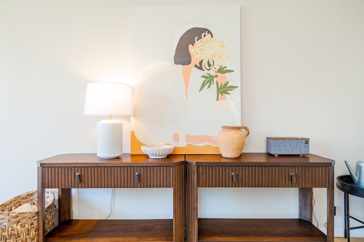 A wooden console table with a white lamp, a vase, and a radio.