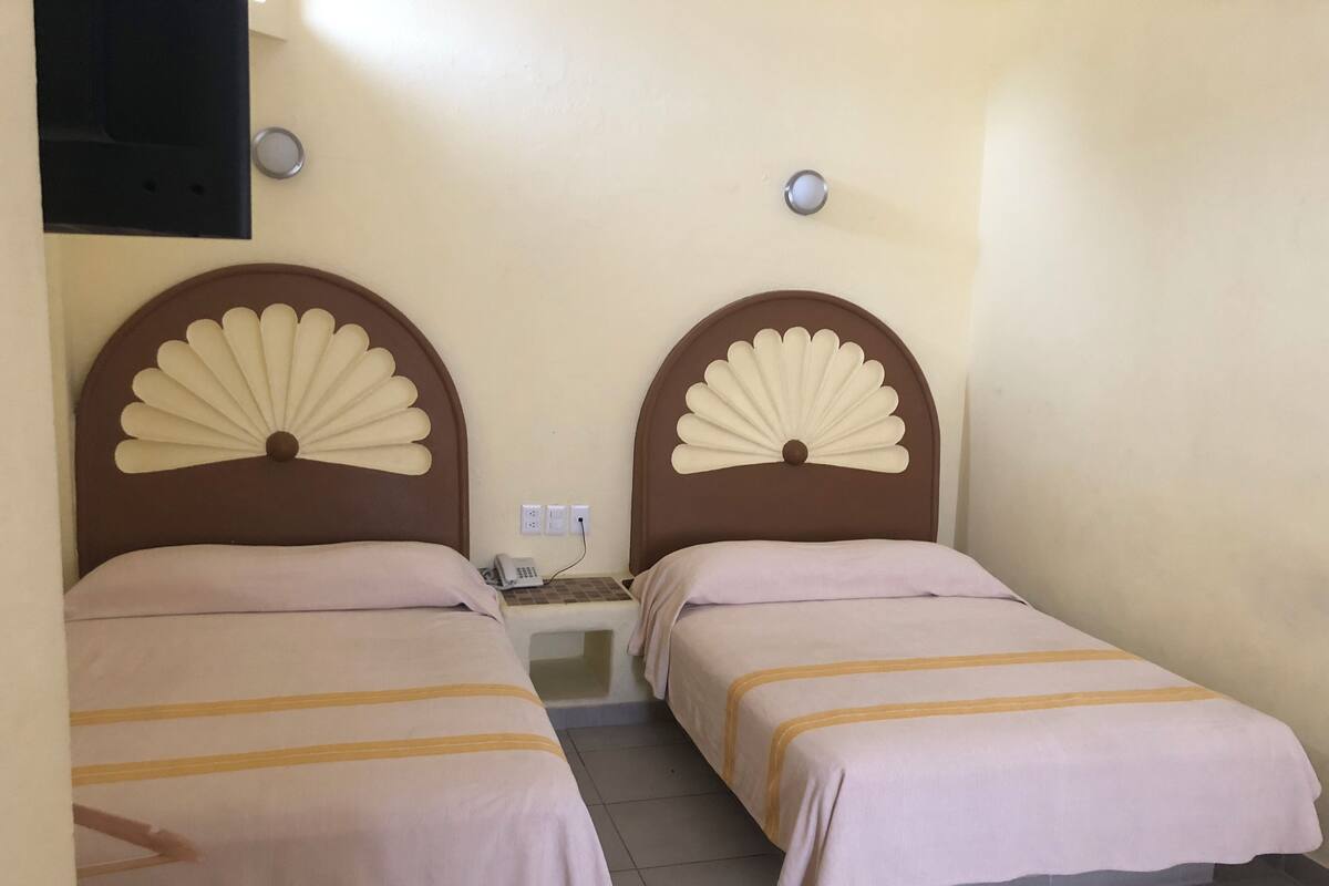 Een kamer met twee bedden, elk met een ander hoofdeinde, een klein nachtkastje en een tv aan de muur.