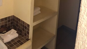 Ett badrum med ett kaklat golv, en vit handfat och en handdukshängare med krokar.