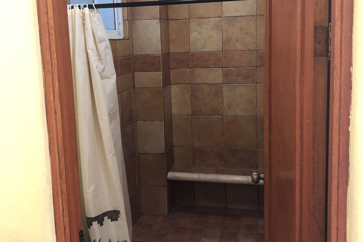 Een badkamer met een douche, toilet en raam.
