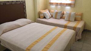 Ett hotellrum med två separata sängar, var och en med ett randigt överkast och kuddar.