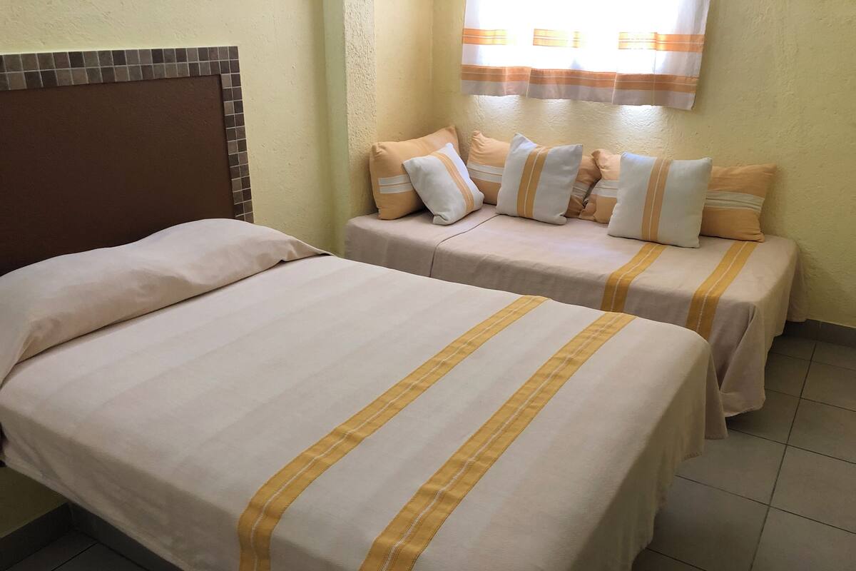 Een hotelkamer met twee enkele bedden, elk met een gestreept dekbed en kussens.