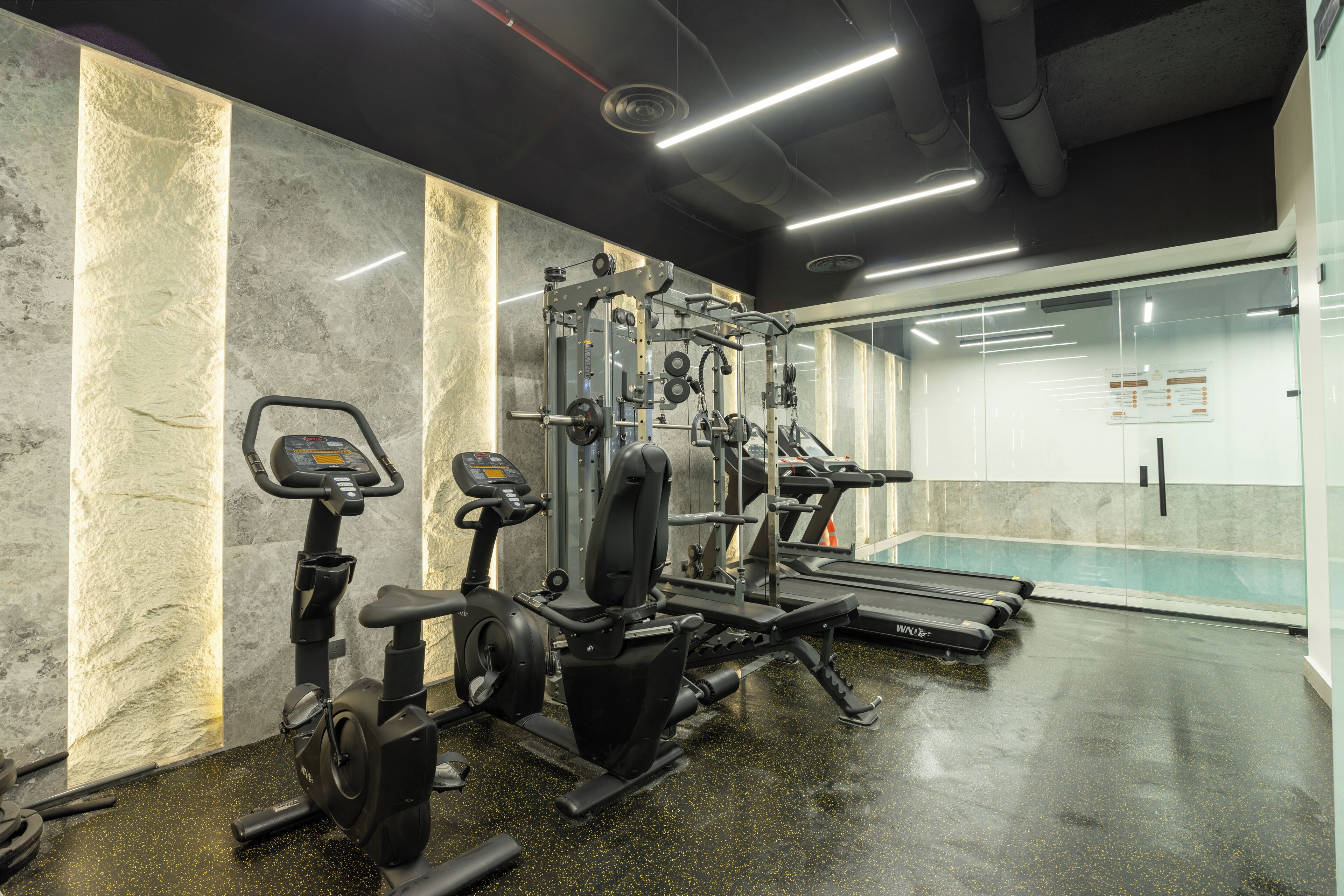 A gym with various exercise equipment, a treadmill, and a mirrored wall.