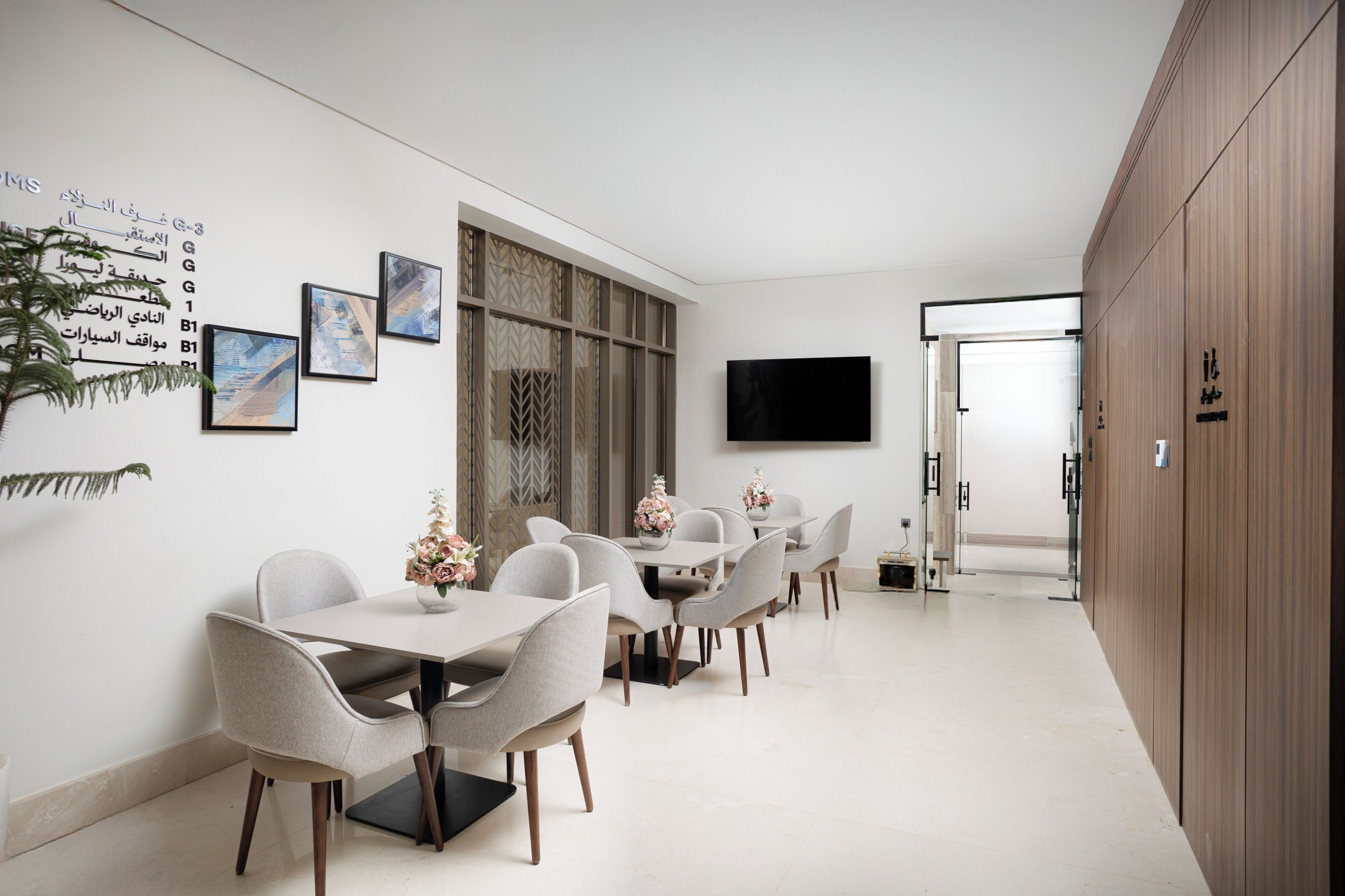 A modern dining area with a long table, chairs, and artwork on the walls.