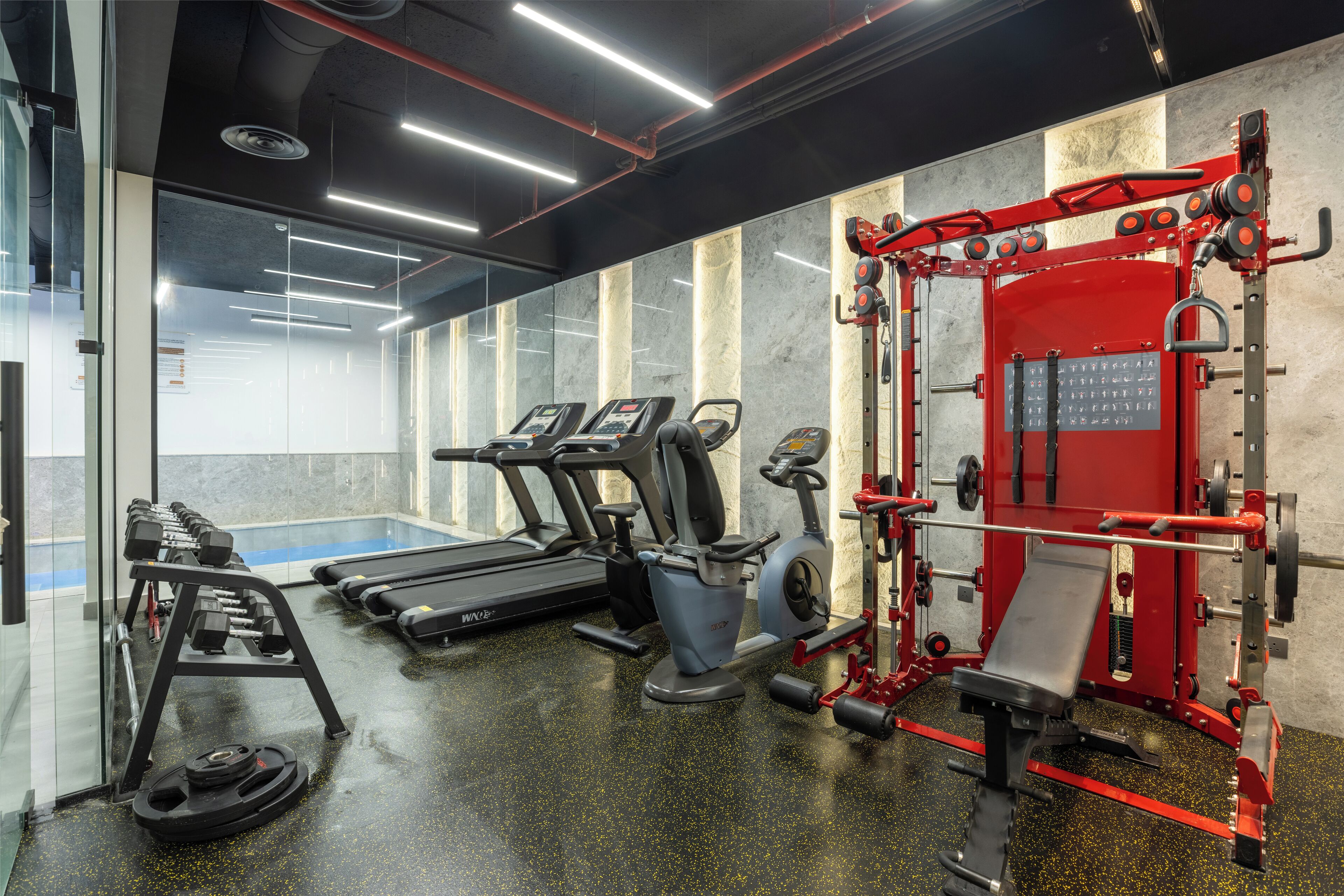 A gym with treadmills, weight machines, and a red Smith machine.