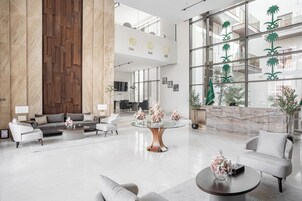 A spacious lobby with a reception desk, seating area, and a large window with decorative palm trees.