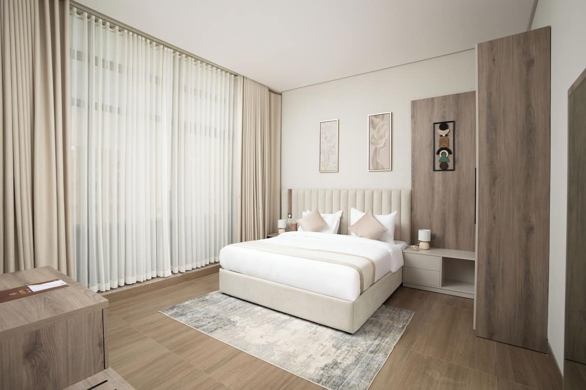 A modern bedroom with a large bed, a wooden wardrobe, and a bedside table.