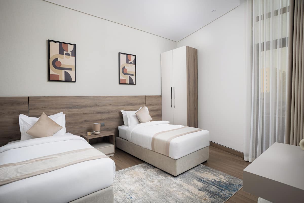 A modern hotel room with two beds, a wardrobe, and artwork on the walls.