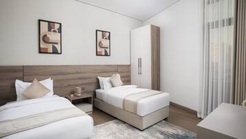 A modern hotel room with two beds, a wardrobe, and artwork on the walls.