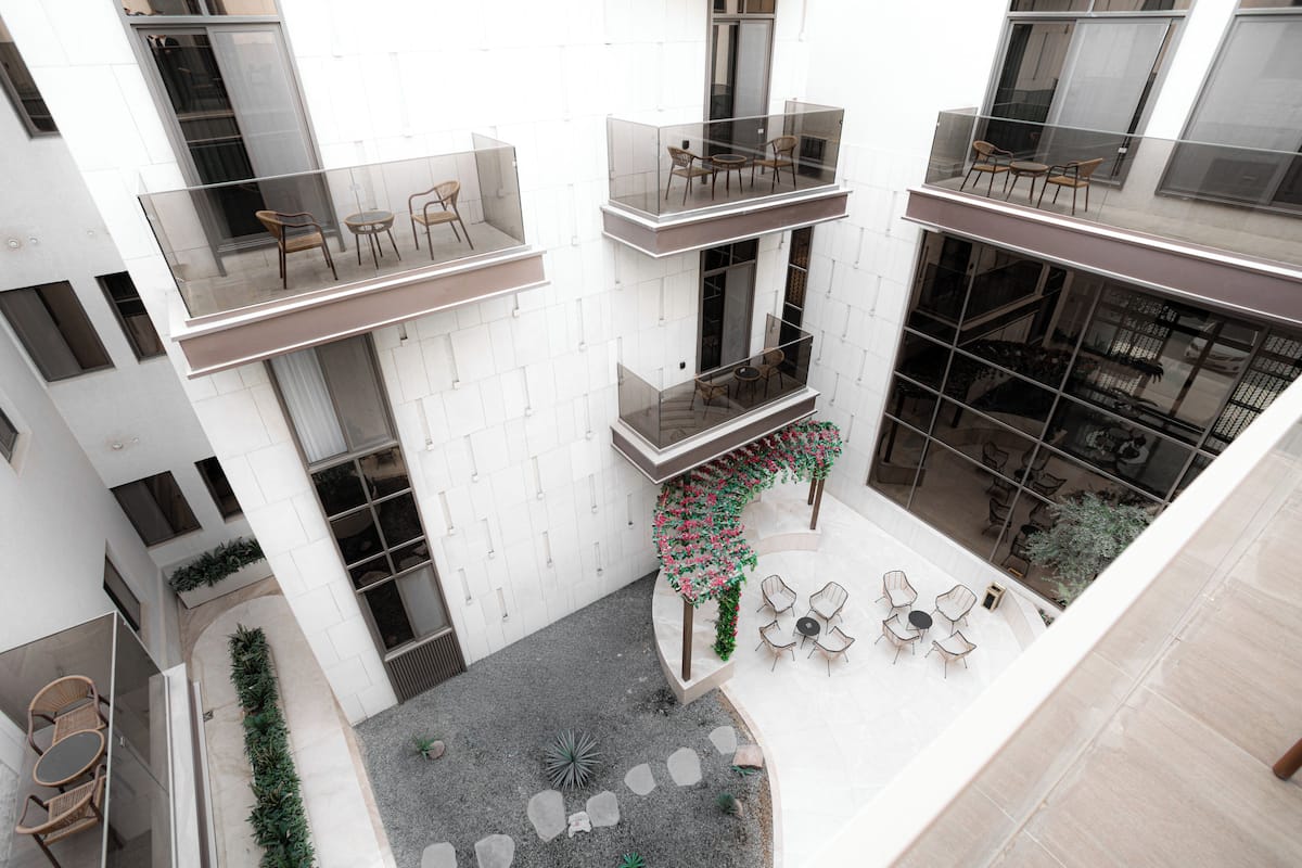 A multi-level building with balconies, outdoor seating, and a central garden area.