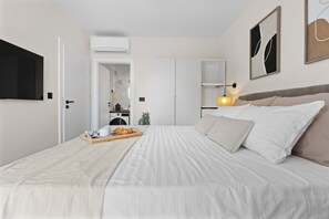 A neatly arranged hotel room with a large bed, a flat-screen TV, a wardrobe, and a small kitchenette. - NEW Charming Villa Harmonia with Heated pool,Indoor Jacuzzi surrounded by nature (Sveta Katarina)